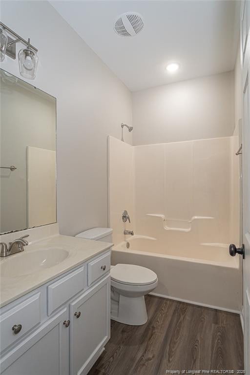 bathroom featuring toilet, wood finished floors, vanity, visible vents, and shower / bathing tub combination