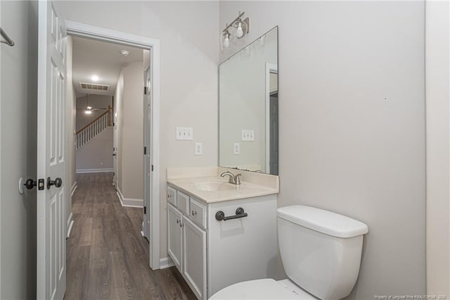 bathroom with visible vents, toilet, vanity, wood finished floors, and baseboards