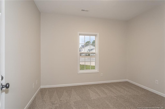 unfurnished room with carpet, visible vents, and baseboards