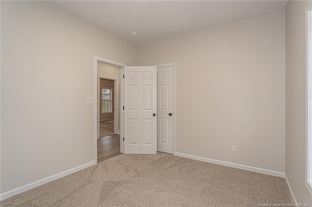 unfurnished room featuring light carpet and baseboards