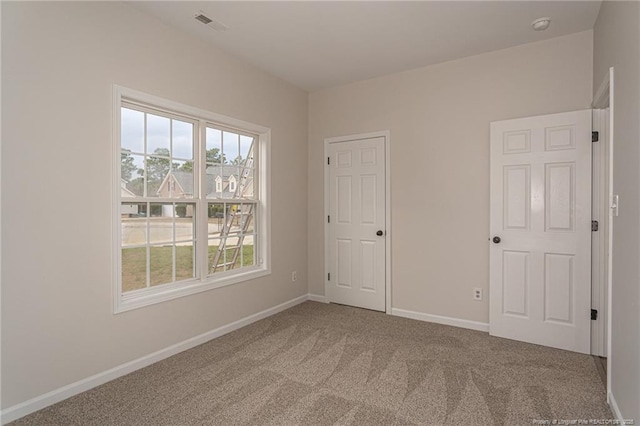 spare room with visible vents, baseboards, and carpet flooring