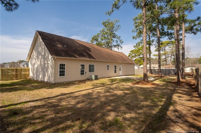 back of house with a fenced backyard, a lawn, and central AC