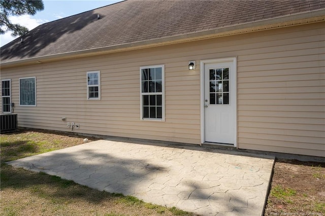 rear view of property featuring a shingled roof, a patio, and central AC unit