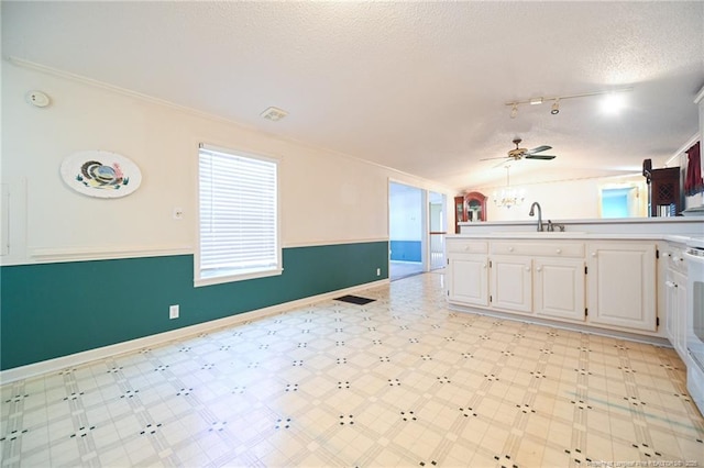 kitchen featuring lofted ceiling, a textured ceiling, light floors, white cabinetry, and a sink