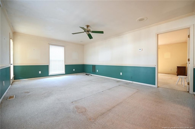 carpeted empty room featuring baseboards, a ceiling fan, visible vents, and crown molding