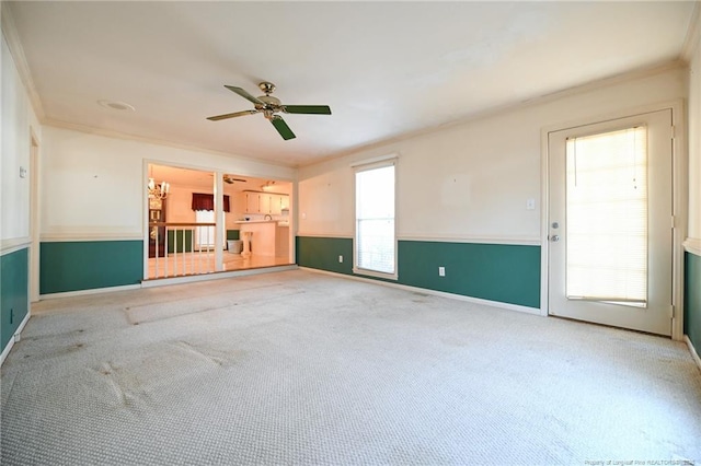 carpeted spare room with ceiling fan, ornamental molding, and baseboards