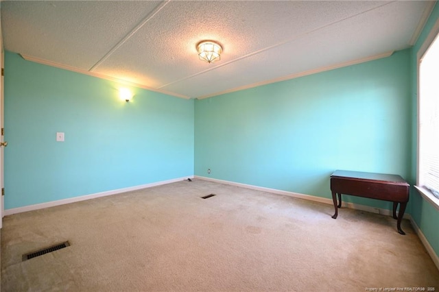 carpeted spare room featuring baseboards, visible vents, a textured ceiling, and ornamental molding