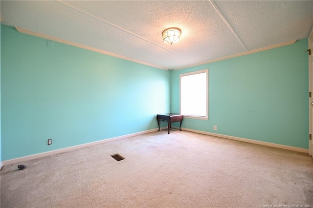 spare room featuring visible vents, ornamental molding, carpet flooring, a textured ceiling, and baseboards