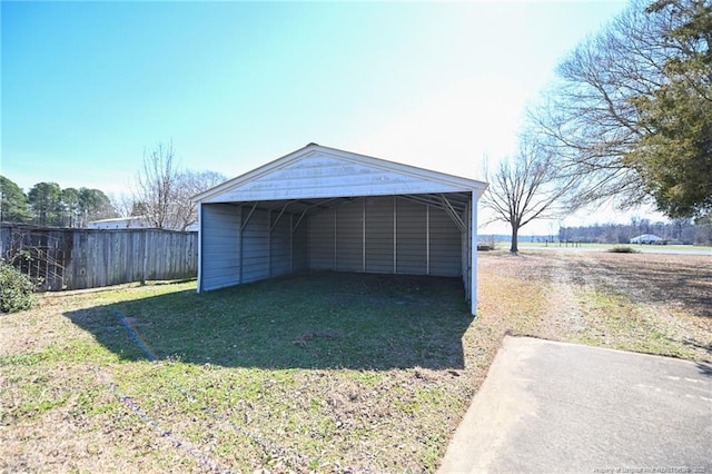 view of outbuilding featuring driveway, fence, and a carport