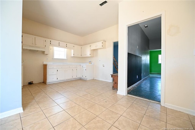 kitchen featuring white cabinets, light countertops, baseboards, and light tile patterned floors