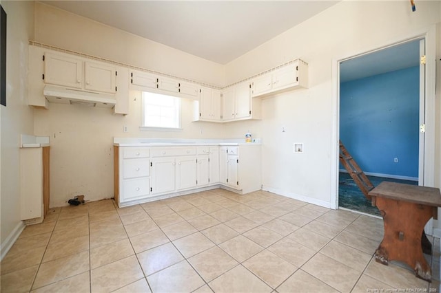 kitchen featuring light countertops, light tile patterned flooring, white cabinetry, and under cabinet range hood