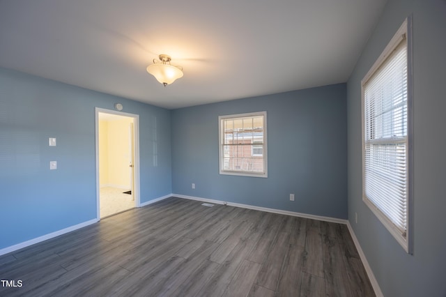 empty room with dark wood-type flooring and baseboards