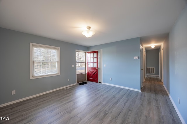 unfurnished room featuring visible vents, baseboards, and wood finished floors