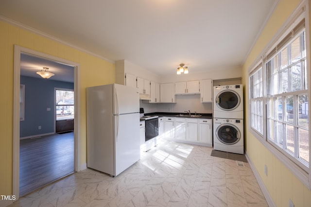 kitchen featuring ornamental molding, stacked washer / drying machine, freestanding refrigerator, marble finish floor, and range with electric stovetop