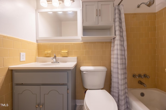 full bath with shower / bath combo, vanity, toilet, and tile walls