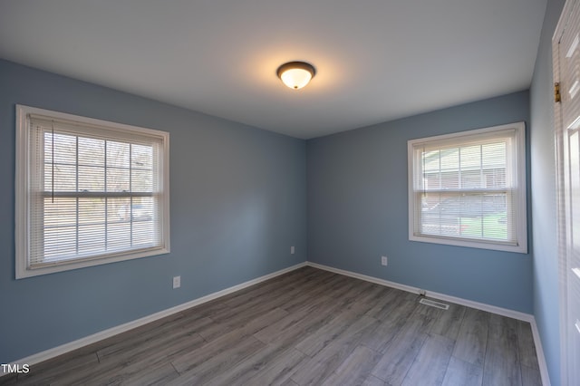 unfurnished room with visible vents, baseboards, and wood finished floors