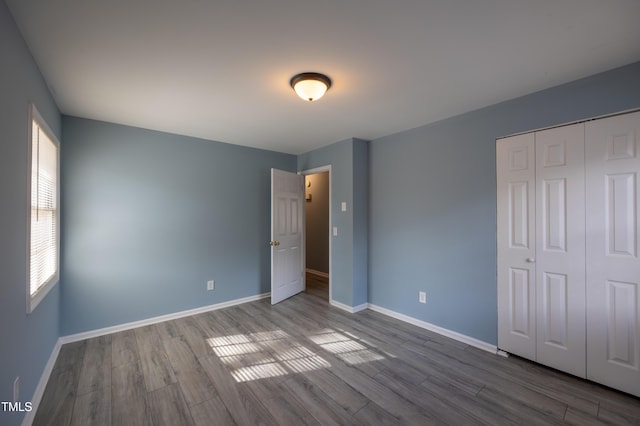 unfurnished bedroom featuring a closet, dark wood finished floors, and baseboards