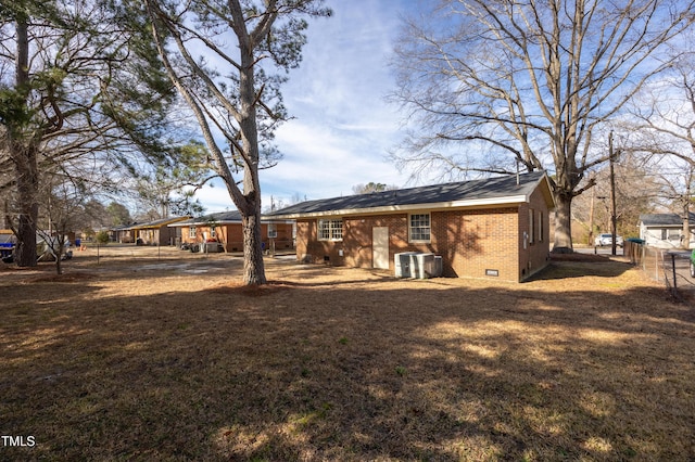 rear view of house featuring cooling unit, crawl space, brick siding, and a lawn