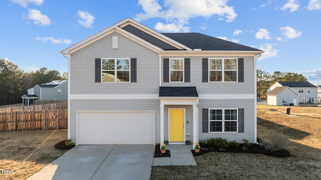 traditional-style home featuring concrete driveway, an attached garage, and fence