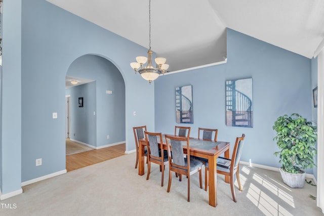 carpeted dining space with arched walkways, an inviting chandelier, lofted ceiling, and baseboards