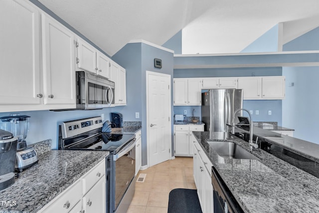 kitchen with vaulted ceiling, appliances with stainless steel finishes, white cabinets, and a sink