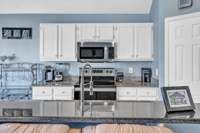 kitchen with appliances with stainless steel finishes, dark stone counters, white cabinets, and a textured ceiling