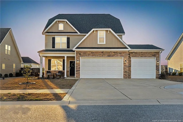 craftsman-style house with an attached garage, covered porch, driveway, stone siding, and board and batten siding