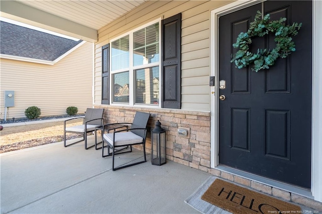 view of exterior entry with stone siding and covered porch