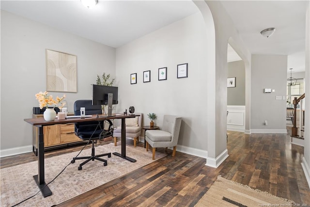 office space featuring an inviting chandelier, baseboards, arched walkways, and wood finished floors