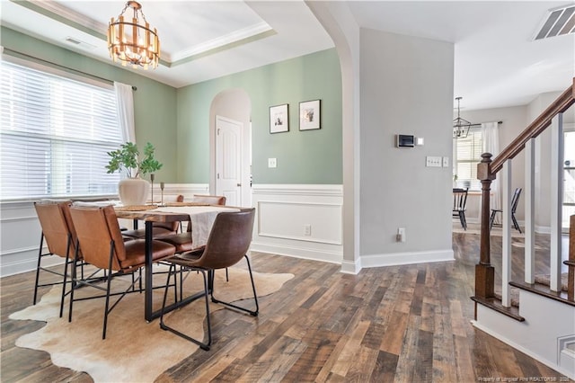 dining area with arched walkways, a notable chandelier, wood finished floors, visible vents, and stairway