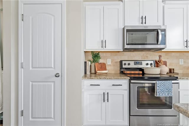 kitchen with stainless steel appliances, white cabinets, light stone counters, and decorative backsplash