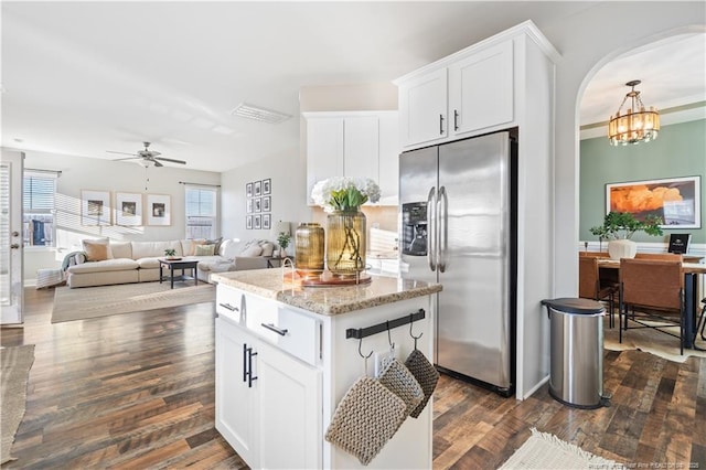 kitchen with arched walkways, stainless steel fridge, dark wood finished floors, and white cabinets