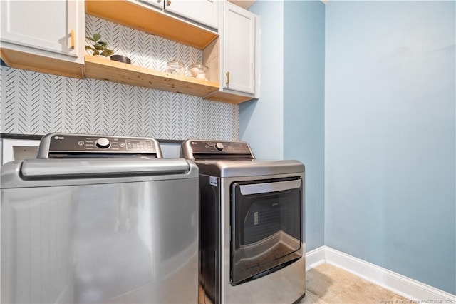 clothes washing area featuring cabinet space, baseboards, and washer and clothes dryer