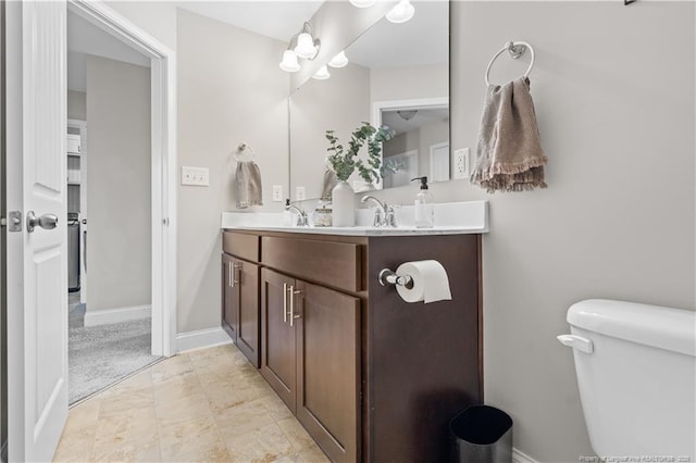 bathroom featuring toilet, baseboards, and vanity