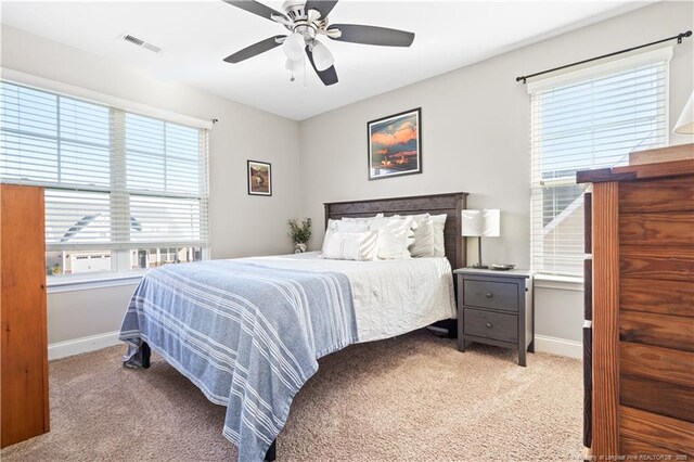 carpeted bedroom featuring a ceiling fan, visible vents, and baseboards