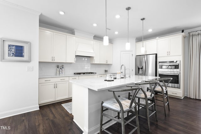 kitchen with dark wood-style flooring, white cabinets, appliances with stainless steel finishes, decorative backsplash, and a kitchen bar