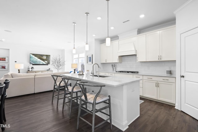 kitchen featuring tasteful backsplash, dark wood-style flooring, a sink, and gas stovetop