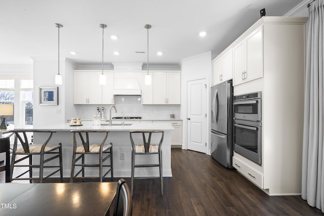 kitchen featuring a breakfast bar area, dark wood-style flooring, light countertops, appliances with stainless steel finishes, and decorative backsplash