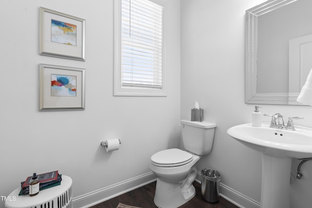 half bath featuring a sink, wood finished floors, toilet, and baseboards