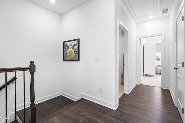 hall with baseboards, attic access, visible vents, and dark wood-type flooring