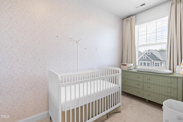 bedroom featuring wallpapered walls, visible vents, a nursery area, and light colored carpet