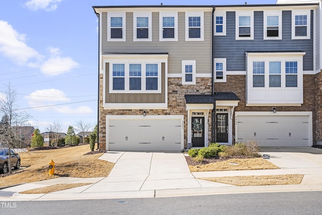 multi unit property with stone siding, an attached garage, and driveway