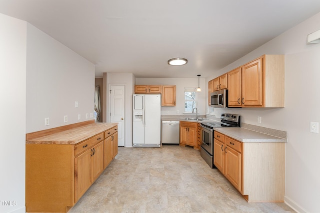 kitchen with appliances with stainless steel finishes, light countertops, a sink, and baseboards