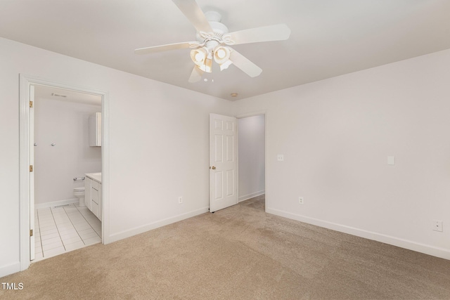 unfurnished bedroom with light tile patterned floors, baseboards, light colored carpet, ensuite bath, and ceiling fan