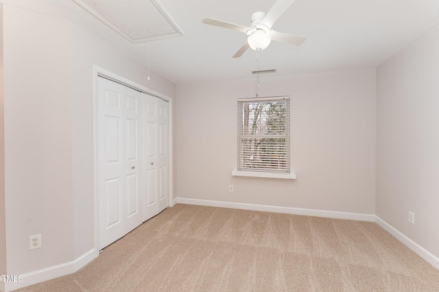 unfurnished bedroom featuring a closet, carpet, attic access, and baseboards