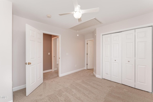 unfurnished bedroom with light carpet, attic access, baseboards, and a closet