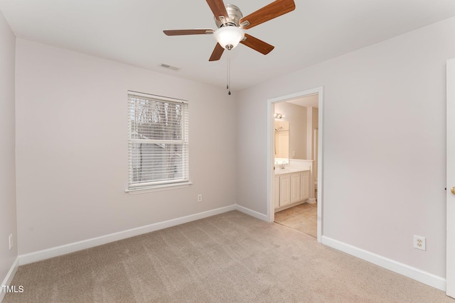 unfurnished bedroom featuring visible vents, ensuite bathroom, light carpet, ceiling fan, and baseboards