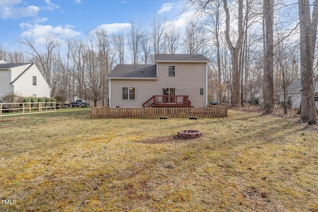 rear view of house featuring a lawn, a fire pit, a wooden deck, and fence