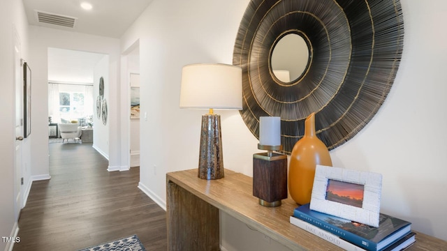 hall featuring baseboards, visible vents, and wood finished floors