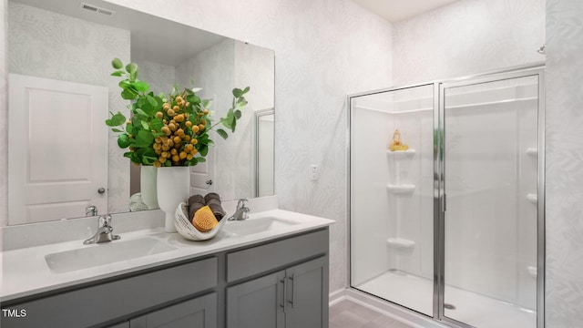 full bath with double vanity, a shower stall, visible vents, and a sink